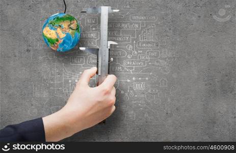 Idea concept. Close up of business person hand measuring Earth planet. Elements of this image are furnished by NASA