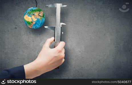 Idea concept. Close up of business person hand measuring Earth planet. Elements of this image are furnished by NASA