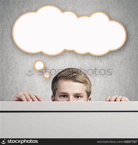 Idea concept. Half face of young man looking out from under table
