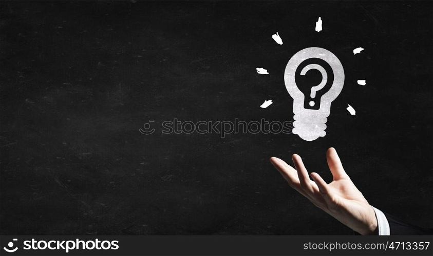 Idea concept. Human hand and light bulb drawn with chalk