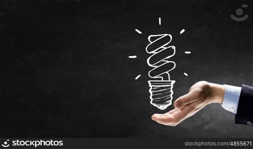 Idea concept. Human hand and light bulb drawn with chalk