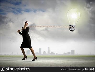 Idea concept. Image of businesswoman pulling electrical bulb with rope