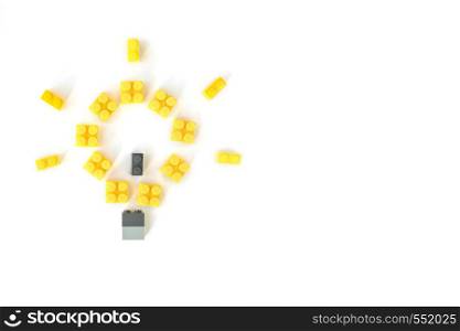 Idea concept. Lamp made of yellow plastic constructor bricks on white background. Popular toys.. Idea concept. Lamp made of plastic constructor bricks on white background. Popular toys. Copyspace