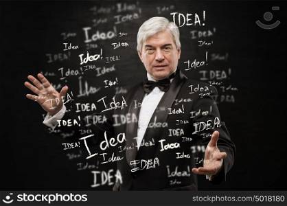 Idea concept. Mature business man standing on black background with idea signs in front
