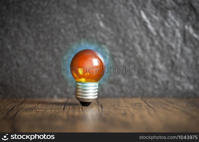 idea concept with orange light bulb and blue light on wooden with dark background
