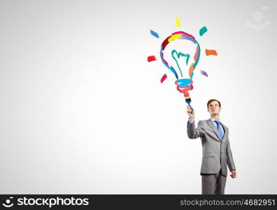 Idea concept. Young businessman with paint brush in hand