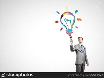 Idea concept. Young businessman with paint brush in hand
