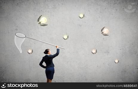 Idea concept. Young businesswoman catching light bulb with hoop