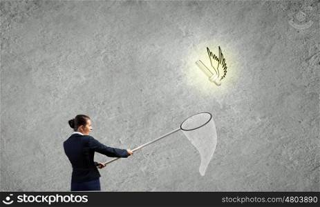 Idea concept. Young businesswoman catching light bulb with hoop