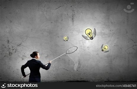 Idea concept. Young businesswoman catching light bulb with hoop