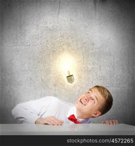 Idea concept. Young man looking up at electric bulb