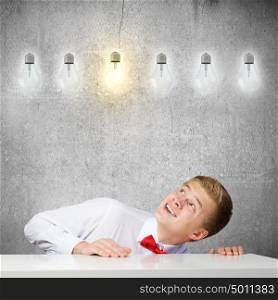 Idea concept. Young man looking up at electric bulb