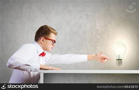 Idea concept. Young man pointing at electric bulb with finger