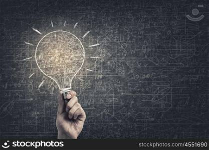 Idea for business plan. Glowing light bulb illuminating business sketches on wall