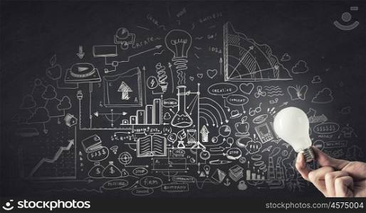 Idea for business plan. Glowing light bulb illuminating business sketches on wall