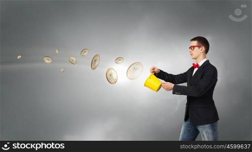 Idea for progressive growth. Young funny man in glasses with yellow bucket in hands