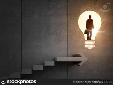 Idea for successful progress and promotion. Back view of businessman standing on ladder and big idea bulb