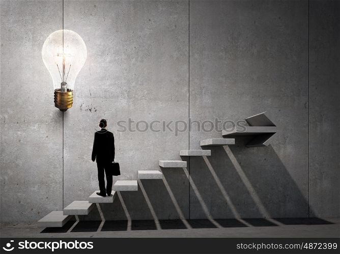 Idea for successful progress and promotion. Back view of businessman standing on ladder and big idea bulb