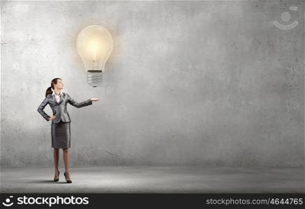 Idea generator. Attractive businesswoman holding light bulb in palm
