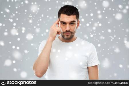 idea, inspiration, winter, christmas and people concept - man pointing finger to his temple over snow on gray background