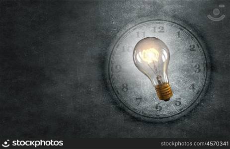 Idea oncept. Conceptual image with light bulb and clock on dark background