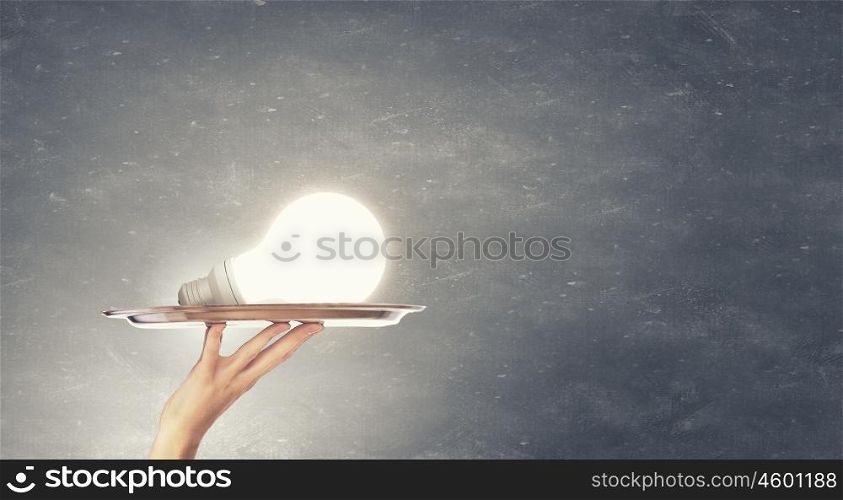 Idea presentation. Hand holding tray with glowing light bulb