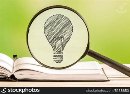 Idea search with a pencil drawing of a light bulb in a magnifying glass
