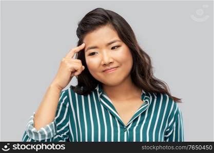idea, solution and decision concept - thinking asian young woman over grey background. thinking asian woman over grey background