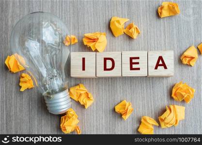 IDEA text wood cube and crumbled paper with lightbulb on wooden table background. Creative, Innovation, Imagination, inspiration, Solution, Strategy and GOAL concept