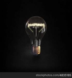 Ideas for business. Glowing glass light bulb with investment word inside