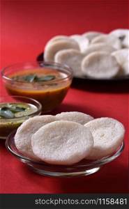 Idli with Sambar and coconut chutney on red background, Indian Dish : south Indian favourite food rava idli or semolina idly or rava idly, served with sambar and green chutney.
