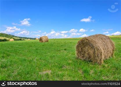 Idyllic farm field with hay bales on the blue sky background