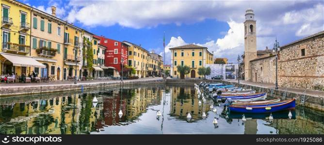 Idyllic lake scenery - tranquil beautiful village (town) Peschiera del Garda with fishing boats and colorful houses. Lago di Garda, northern Italy 4.11.2020