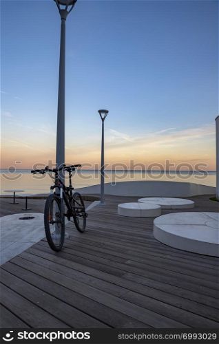 Idyllic scene of a bicycle standing near the sea propped on a pillar with blue sky as background