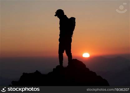 Idyllic sunset with a mountaineer iin silhuettes n summit