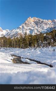 Idyllic winter landscape: stunning mountain range, beautiful river, snowy trees and blue sky