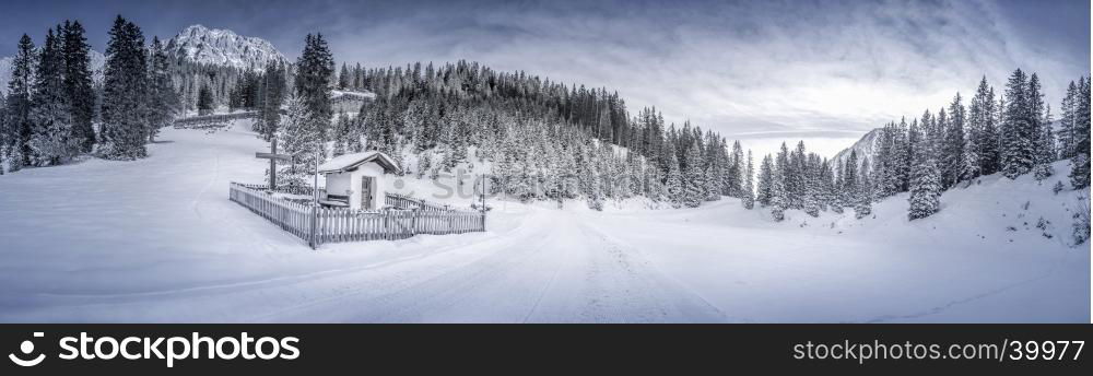 "Idyllic winter panorama with a snowy forest and a small chapel, called "Pestkapelle", build in 1639 as a thank you for the end of a plague. Landscape caught in the Austrian alpine forests, the Ehrwald resort."