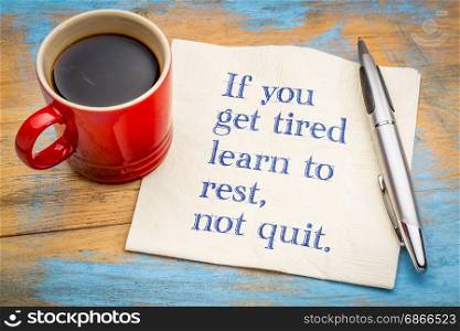 If you get tired learn to rest, not quit - inspirational handwriting on a napkin with a cup of coffee