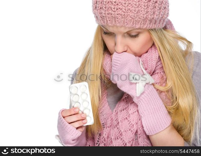 Ill girl in winter clothes holding pills pack