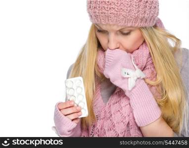 Ill girl in winter clothes holding pills pack
