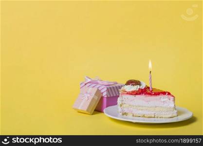 illuminated candle slice cake with two gift boxes against yellow background. Resolution and high quality beautiful photo. illuminated candle slice cake with two gift boxes against yellow background. High quality beautiful photo concept