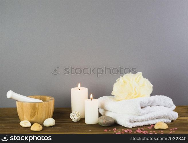illuminated candles towel spa stones loofah mortar pestle wooden surface