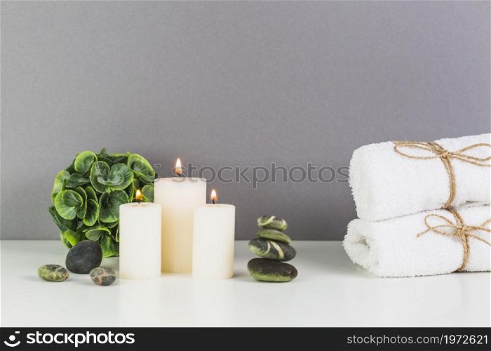 illuminated candles towel spa stones white tabletop. High resolution photo. illuminated candles towel spa stones white tabletop. High quality photo