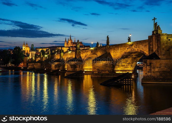 Illuminated Charles Bridge on river Vltava in Prague at sunset