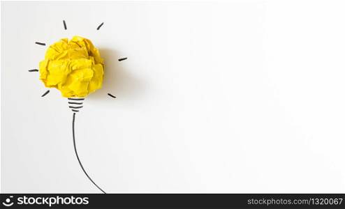 Illuminated crumpled yellow paper light bulb idea on white background