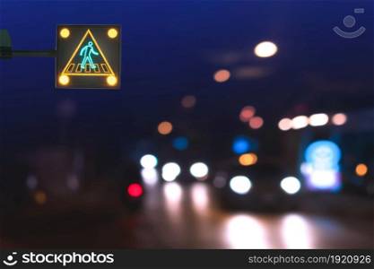 Illuminated electric traffic light pedestrian crossing sign with blurred night city street background