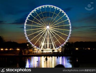 Illuminated ferris wheel and river Seine in Paris at sunset, France