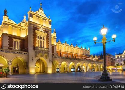 Illuminated palace on old town square at night with dark blue sky. Krakow, Poland