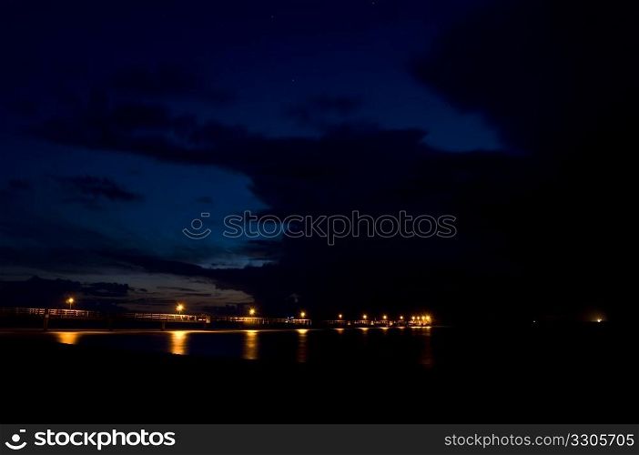illuminated pier going out into the dark waters