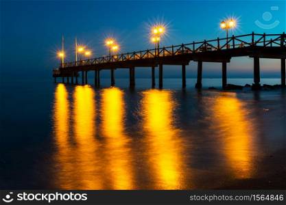 Illuminated wooden jetty on a beach in Marbella during sunset. Long exposure.